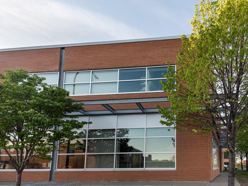 brick office building with glass windows next to trees